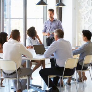 Office meeting, a man standing while others are seated