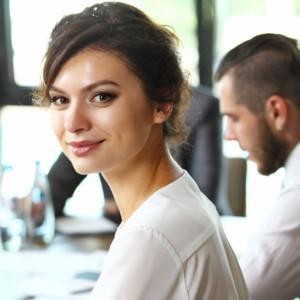 A man and a woman in an office, woman looking at the photographer