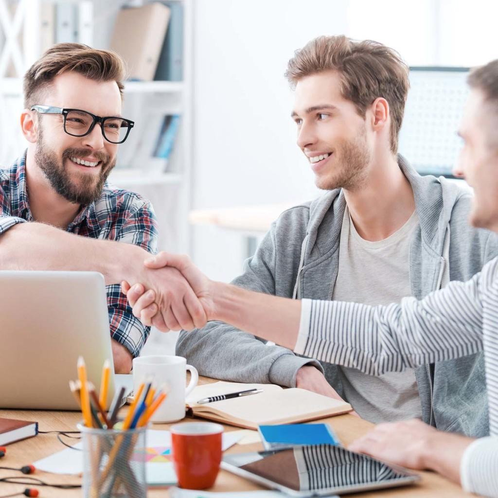 Three men in an office, handshake